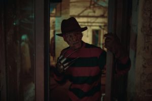 Cosplayer in image of Freddy Krueger from Nightmare on Elm Street film stands in dark